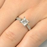 A platinum square-shape diamond single-stone ring, with brilliant-cut diamond line shoulders.