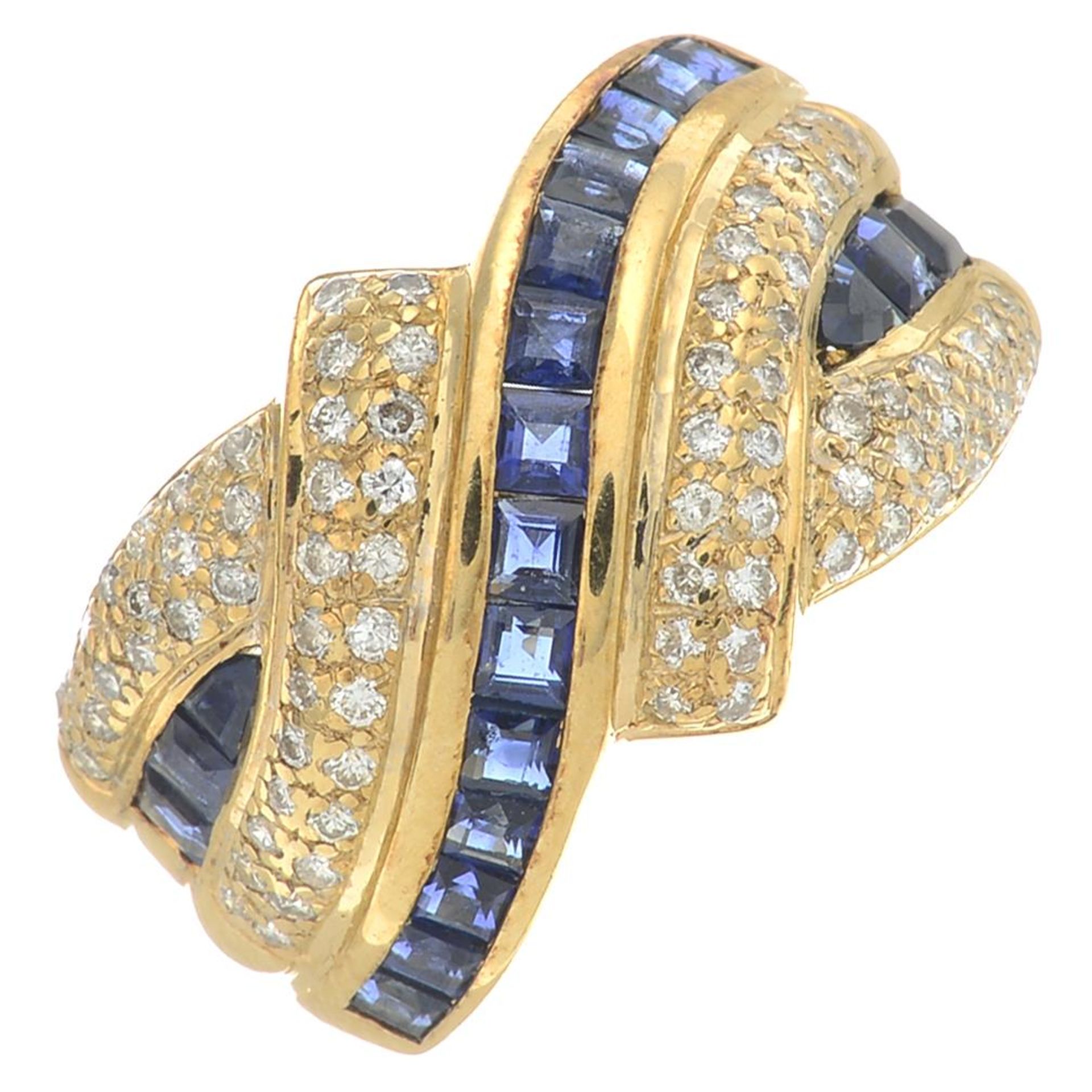 A brilliant-cut diamond and sapphire crossover ring.Estimated total diamond weight 0.45ct.Ring size