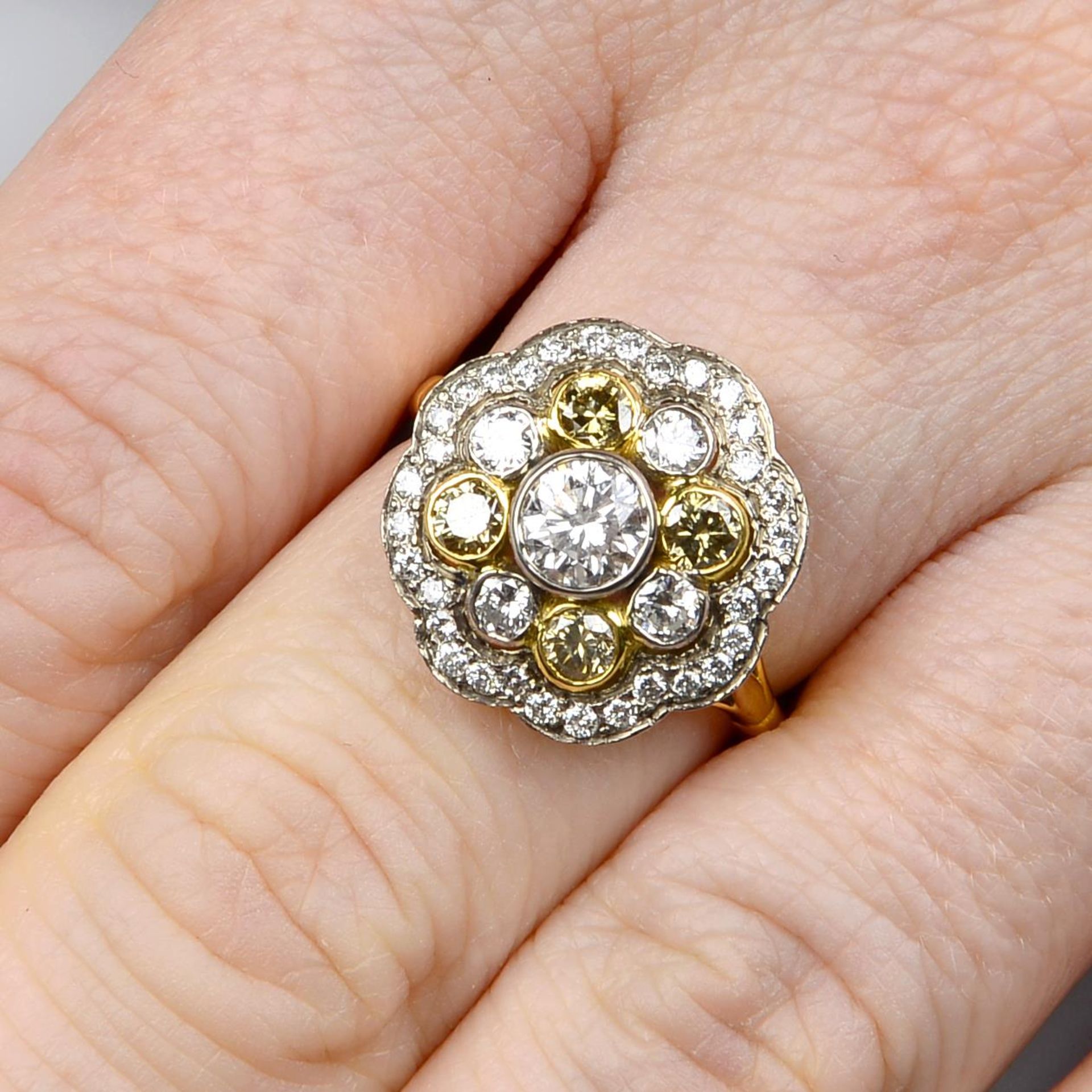 A brilliant-cut 'yellow' diamond and brilliant-cut diamond cluster ring.Estimated total diamond