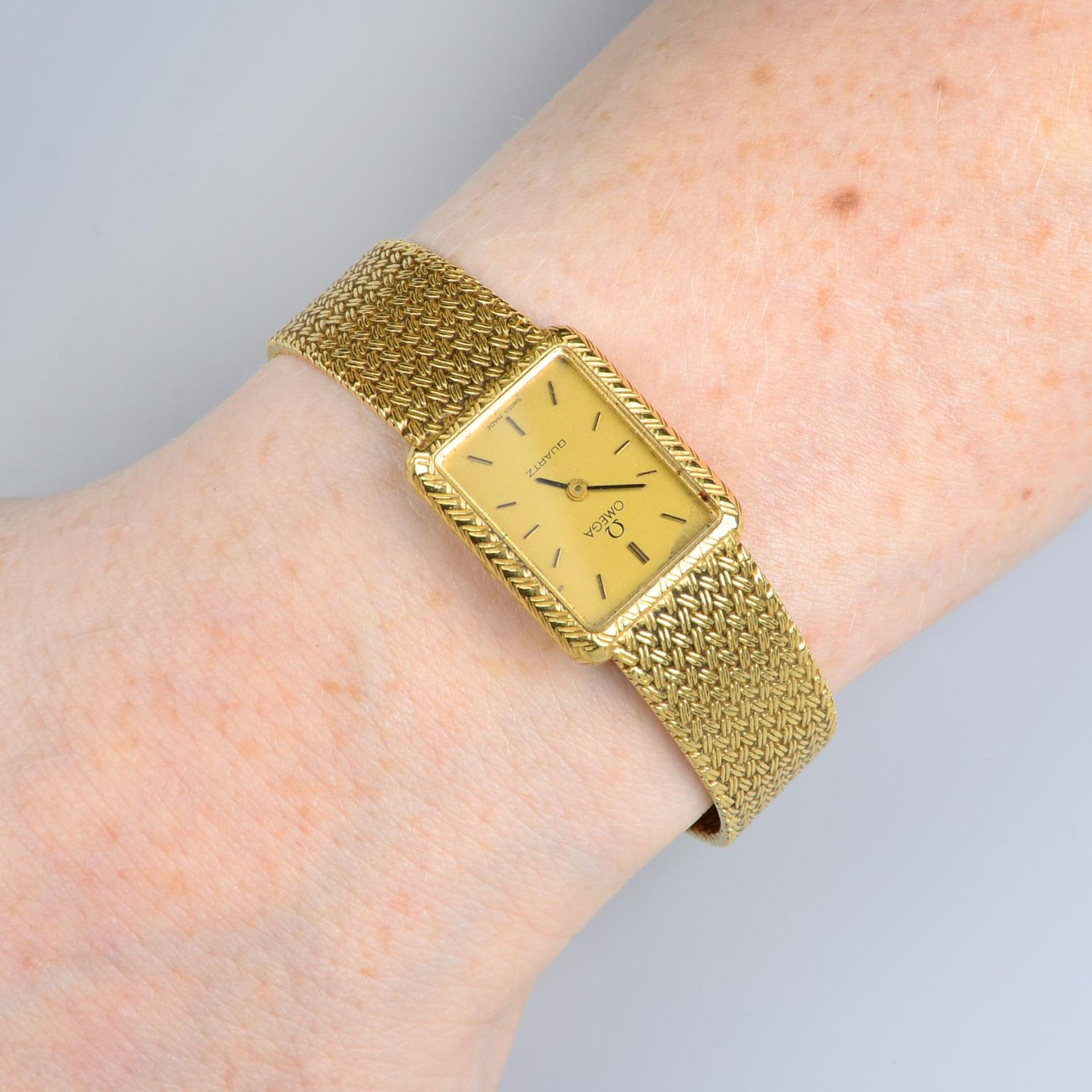 A lady's 18ct gold Omega wrist watch, with integral woven bracelet.Swiss convention marks.