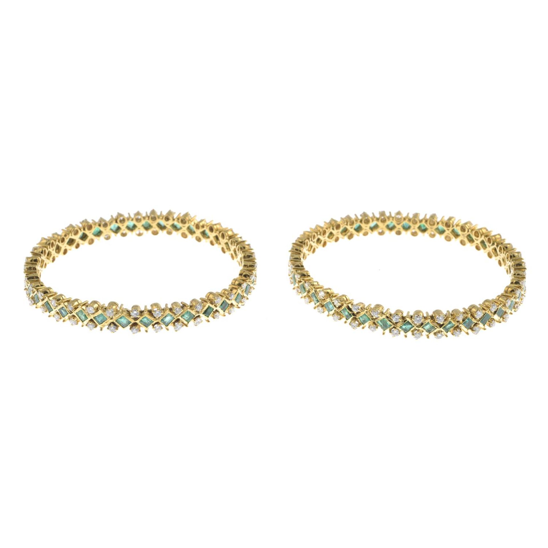 Two vari-cut emerald and brilliant-cut diamond bangles.Estimated total diamond weight 5.50 to