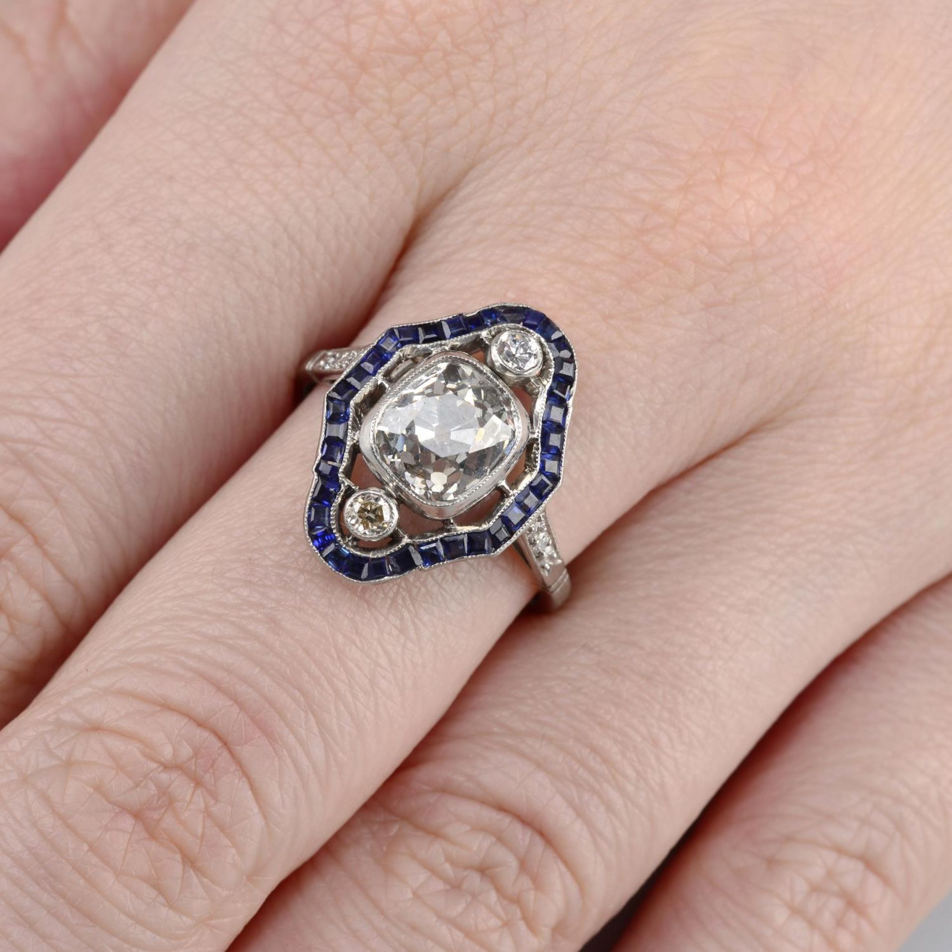 A cushion-shape diamond and sapphire cluster ring.Principal diamond estimated weight 2.20cts,