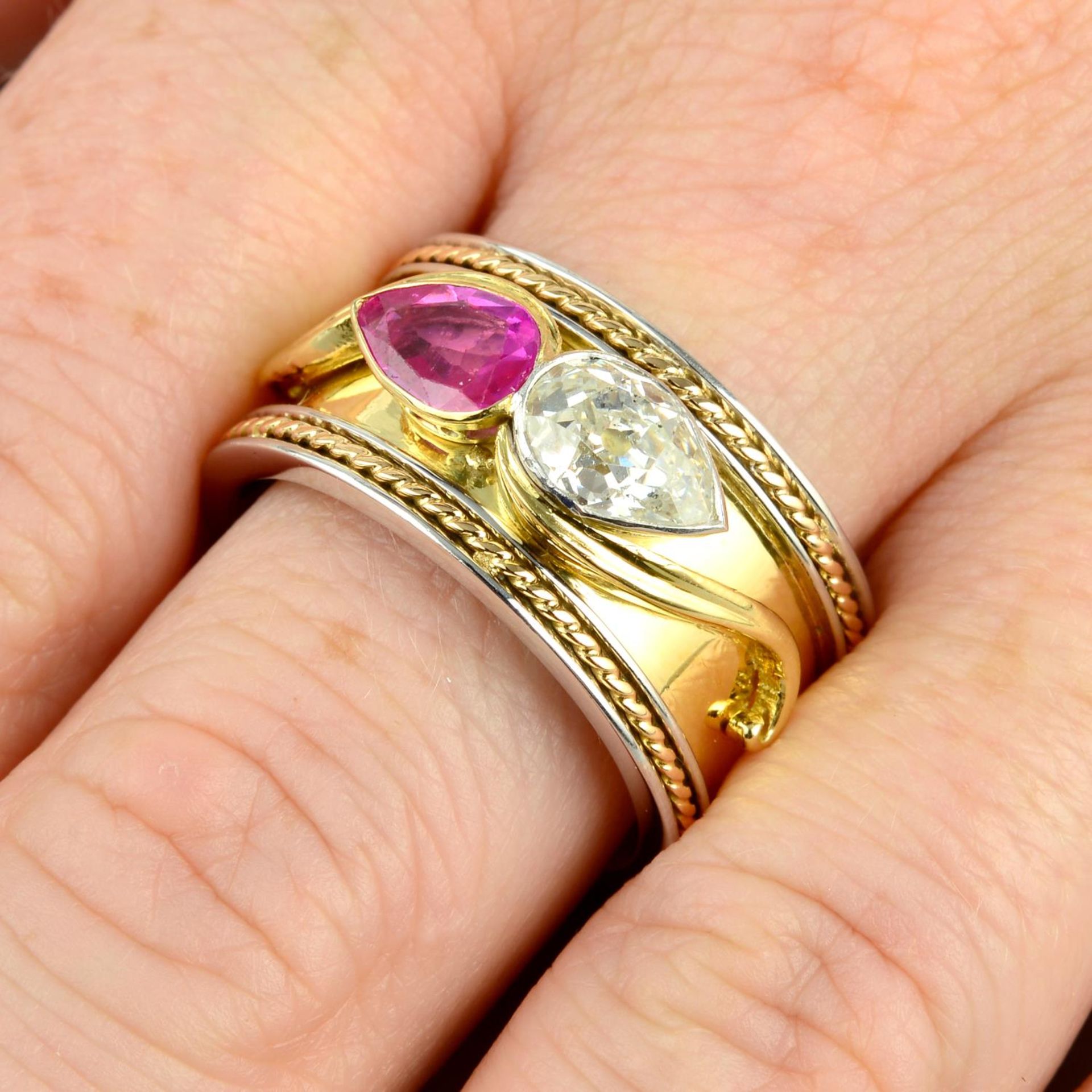 An 18ct gold bi-colour band ring, with pear-shape old-cut diamond and ruby highlights.