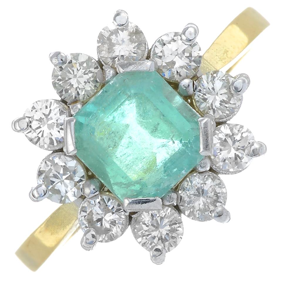 An emerald and brilliant-cut diamond cluster ring.Emerald calculated weight 0.92ct,