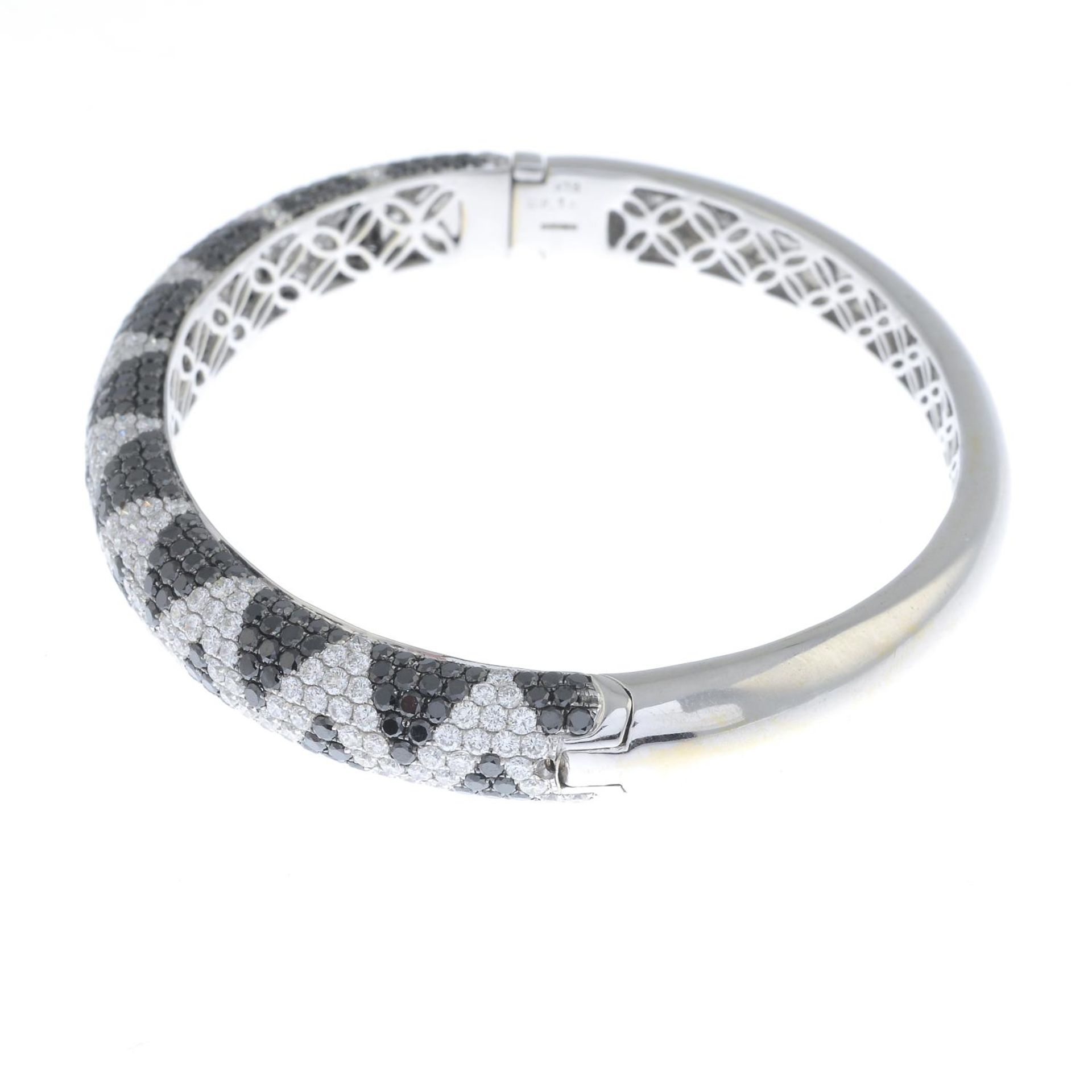 An 18ct gold diamond and black gem bangle, hinged to the plain reverse. - Image 3 of 3