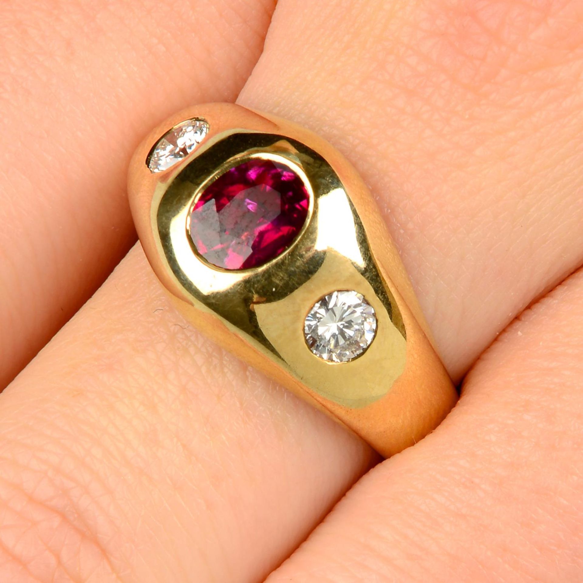 A ruby and brilliant-cut diamond three-stone ring.Ruby calculated weight 0.91ct,