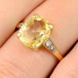 A yellow sapphire single-stone ring, with brilliant-cut diamond shoulders.