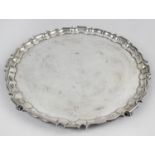 A modern silver salver, of plain circular form with pie crust rim and raised upon four paw feet.