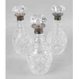 A set of three silver mounted glass decanters,