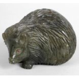 A carved labradorite study of a seated hedgehog,