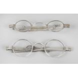 A cased pair of 19th century silver wig spectacles with retractable arms,