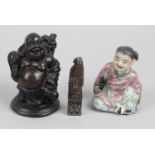 A small oriental pottery figure modelled as a seated child,