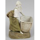 A Royal Dux figure modelled as a young female upstanding and carrying a woven basket,