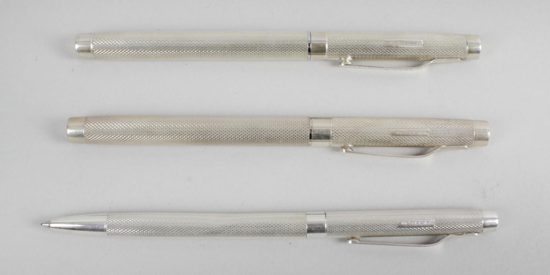 A modern hallmarked silver cased ball point pen (dented) with engine turned decoration and clip