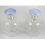 A pair of 1920's silver and enamel mounted glass scent bottles,