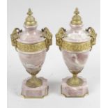 A pair of early 20th century pink marble and gilt metal mounted pedestal urns,