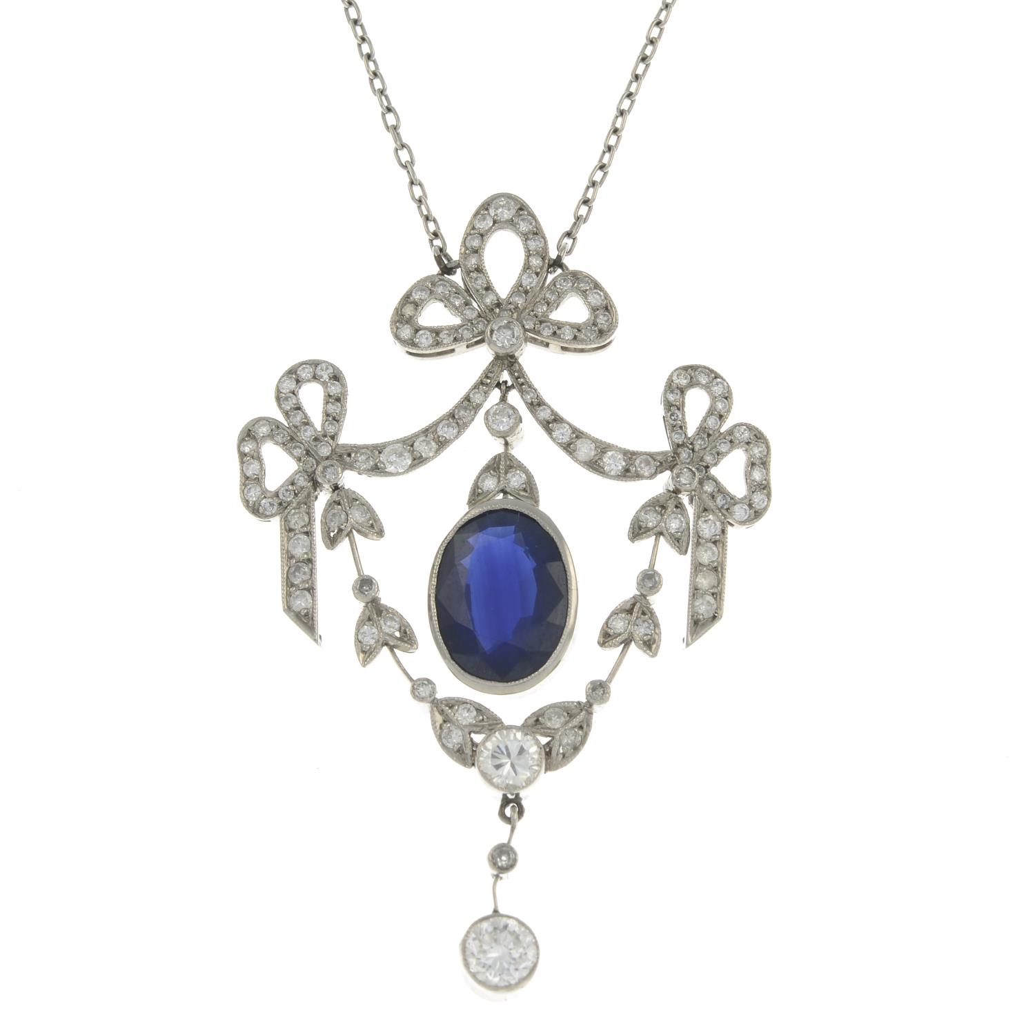 A sapphire and diamond bow pendant, suspended from an integral trace-link chain.