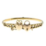 An early 20th century 15ct gold hinged bangle, depicting a heart and a heart-shape padlock.