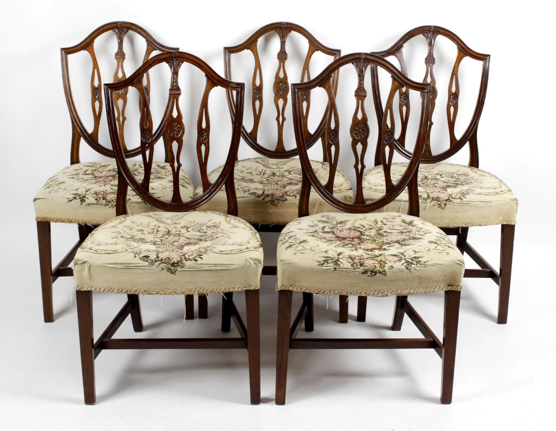 A set of five mahogany framed dining room chairs each with an open carved shield shaped back above