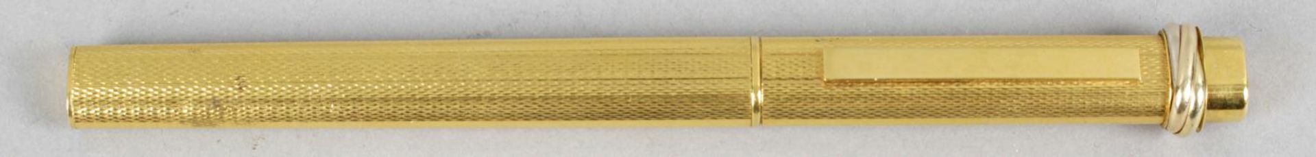 A Must De Cartier gold plated cased ball point pen with vertical engine turned decoration,