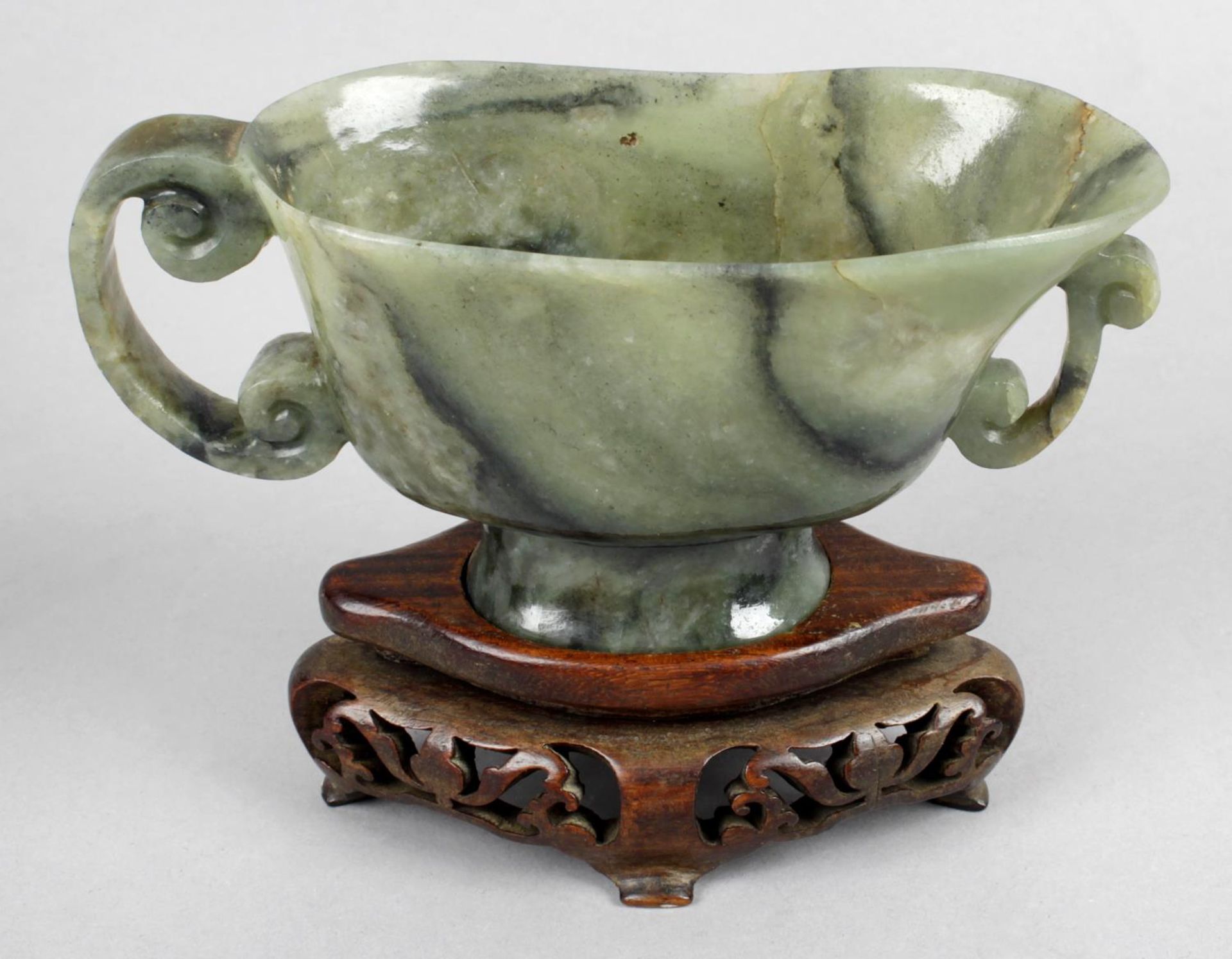 A small collection of carved jadeite to include libation cup upon a carved and pierced wooden