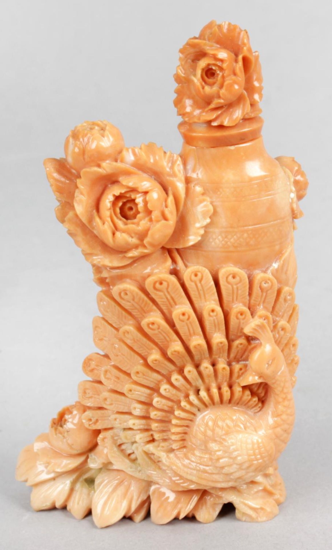 A carved coral snuff bottle and stopper with carved peacock and floral decoration,