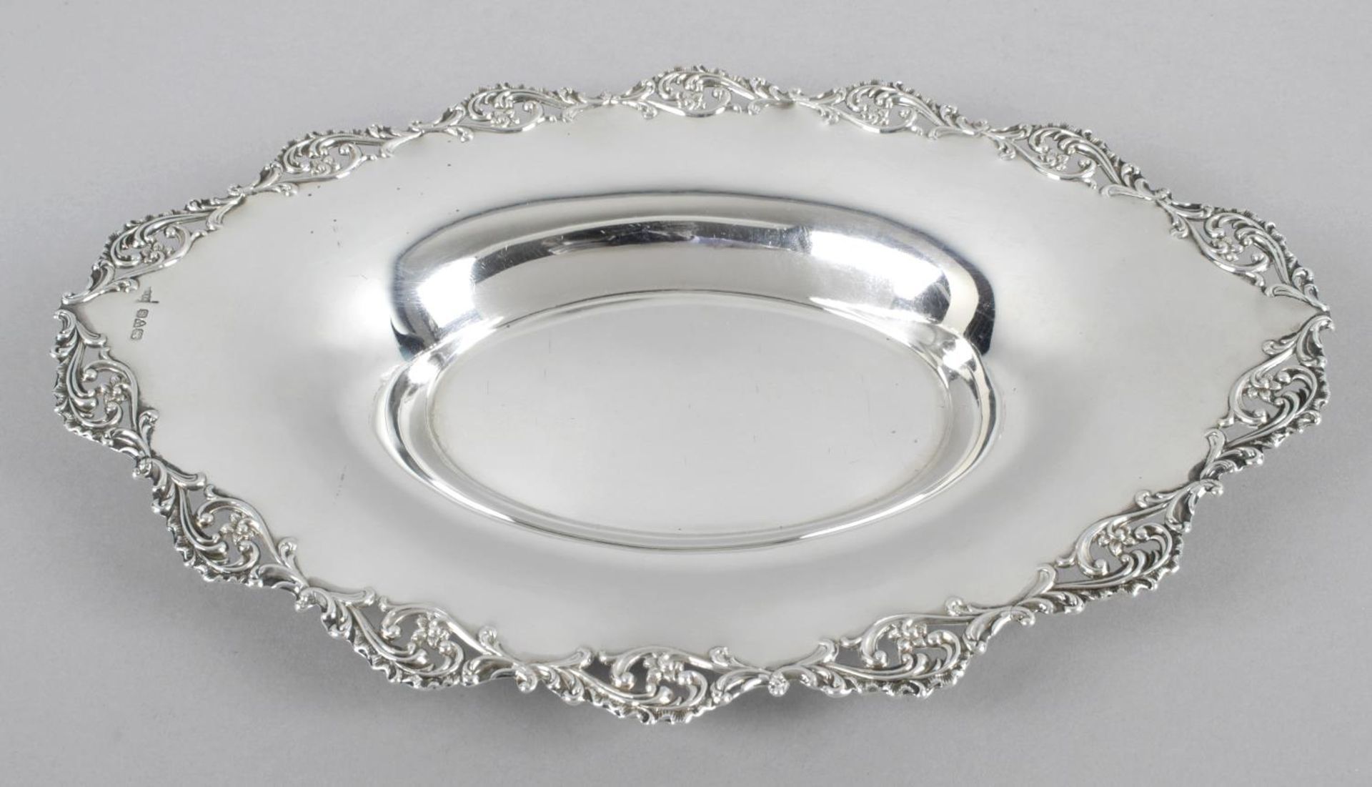 An Edwardian silver oval dish, of plain shallow form with a floral and foliate scroll pierced rim.