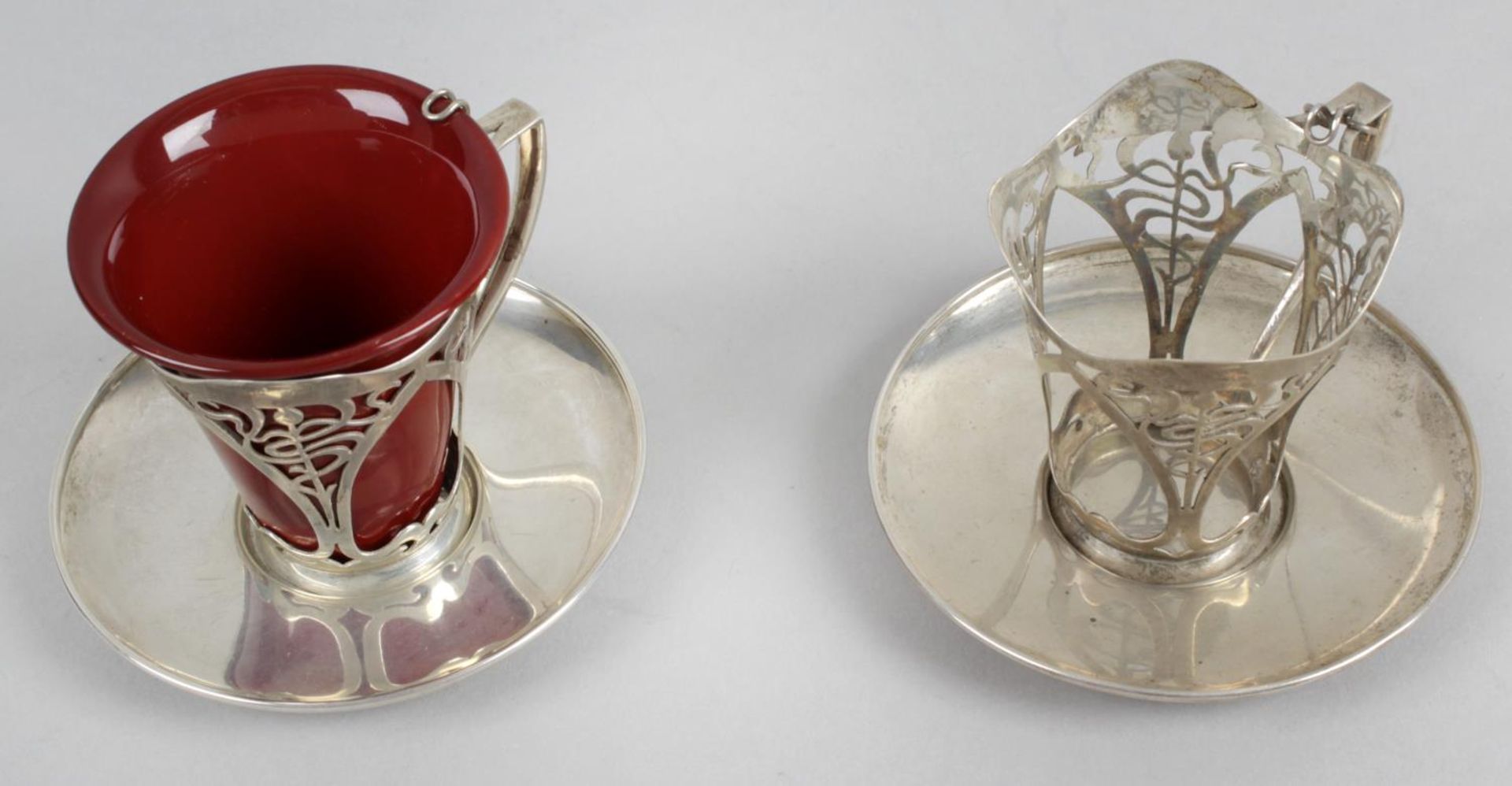 A pair of Art Nouveau silver coffee cup holders and saucers,