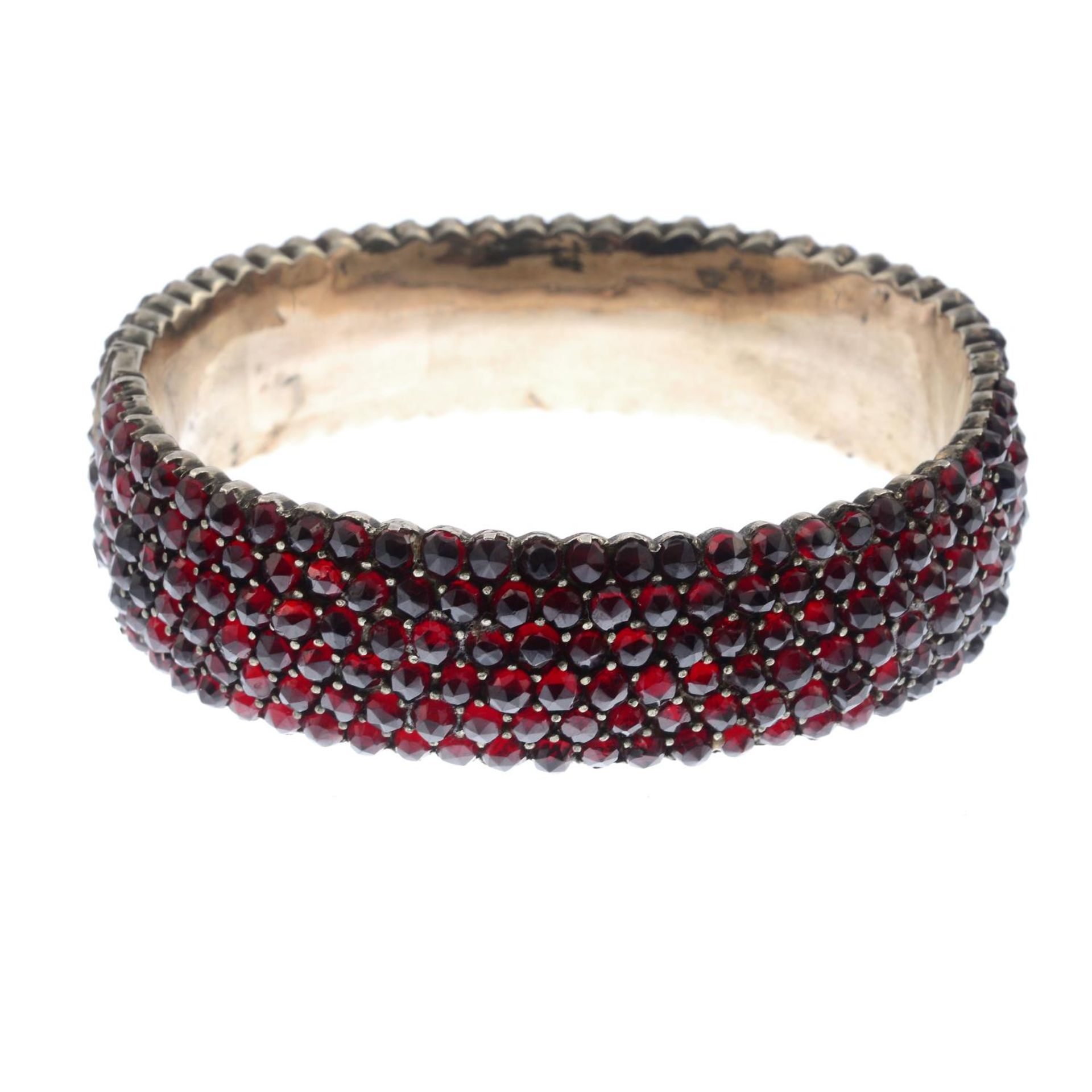 A late 19th century garnet hinged bangle.Inner diameter 6cms.