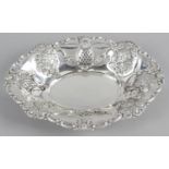 An Edwardian silver bread basket of oval shape with pressed panels of floral decoration alternating