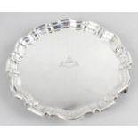 An Edwardian silver round salver with shaped Chippendale style rim standing on three scrolling