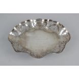 An Irish silver oval pierced dish with floral pattern below a shaped rim standing on four ball