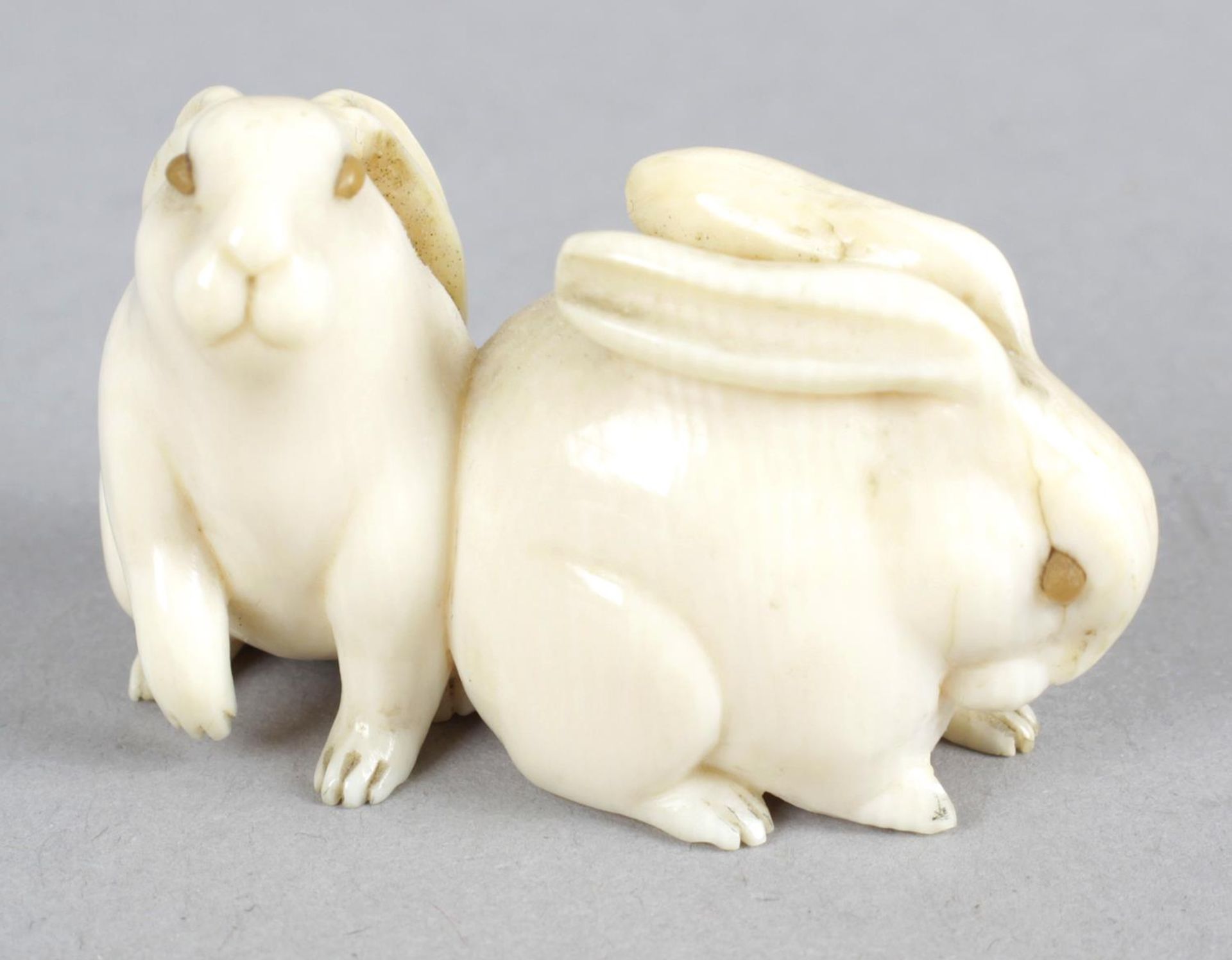 A late 19th century carved ivory netsuke modelled as two rabbits.