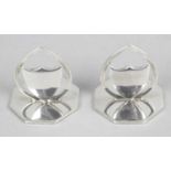 A pair of shield shape silver menu or place name holders, each on an octagonal base.