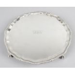 An early 20th century silver round salver with shaped pie crust rim standing on four claw and ball
