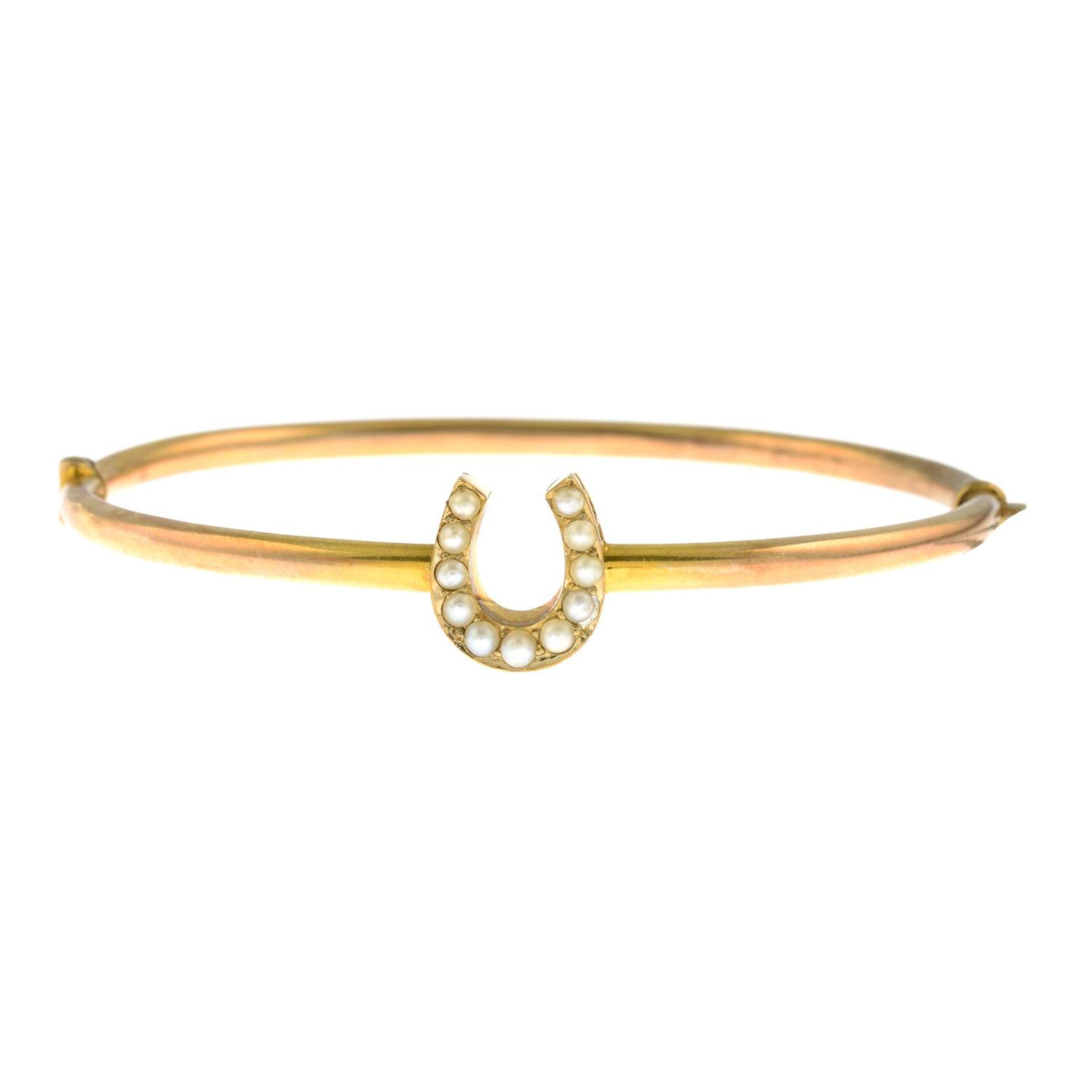 An early 20th century 15ct gold split pearl horseshoe hinged bangle.Stamped 15ct.