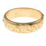 A 1950s 9ct gold bangle, with engraved scrolling floral detail to the front.