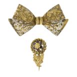 A 19th century gold garnet floral brooch and a silver gilt filigree bow brooch.