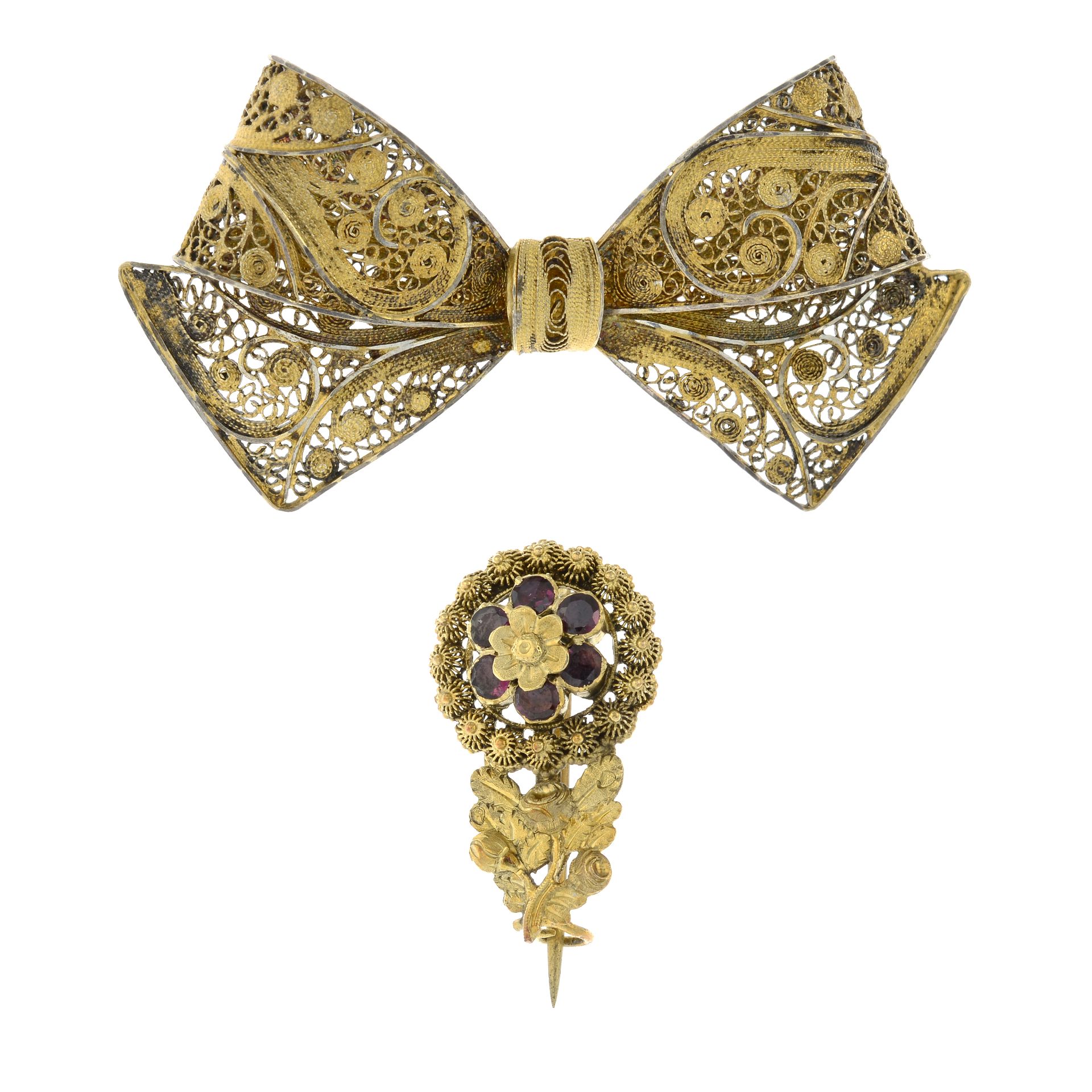 A 19th century gold garnet floral brooch and a silver gilt filigree bow brooch.