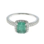 An emerald and diamond cluster ring.Estimated total diamond weight 0.25ct.Stamped 750.Ring size M.