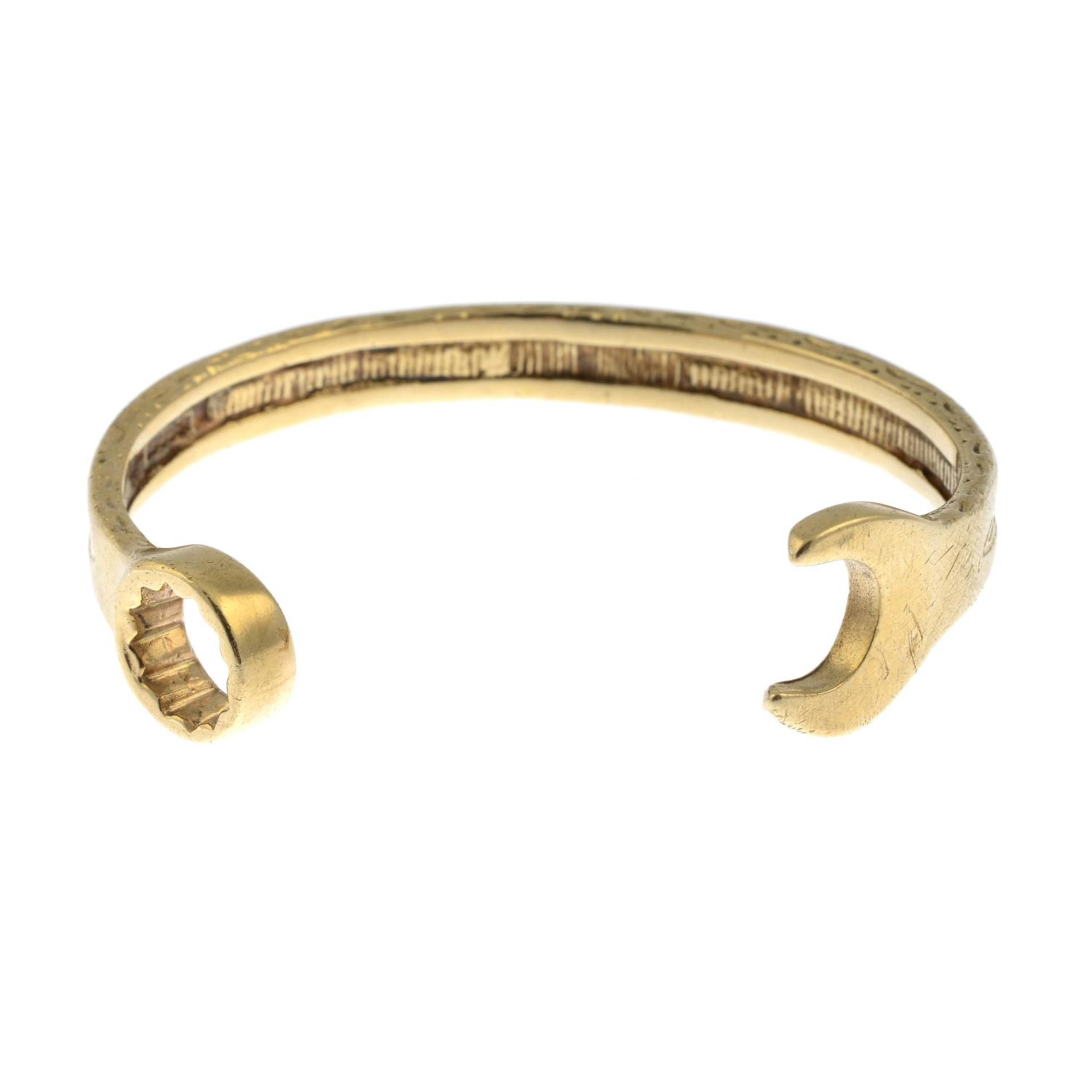 A 9ct gold cuff, depicting a textured spanner.