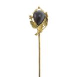 A garnet stickpin, with textured foliate surround.