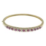 A 9ct gold ruby and diamond hinged bangle.Estimated total diamond weight 0.10ct.Hallmarks for