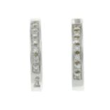 A pair of diamond hoop earrings.Estimated total diamond weight 0.10ct.