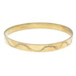 A 9ct gold bangle, with engraved undulating motif.Hallmarks for 9ct gold.