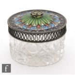 A white metal wired and plique a jour and glass circular jar, the clear cut glass body below