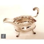 A George II hallmarked silver sauce boat of plain form raised on stepped pad feet and terminating in