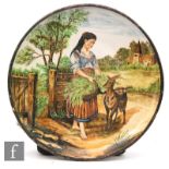 A large late 19th to early 20th Century hand painted maiolica charger decorated with a young farm