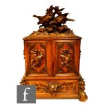 A 19th Century carved walnut Black Forest table cabinet, the top surmounted with carved game birds