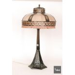 An Art Deco bronze table lamp, the hexagonal swept base with pierced scroll decoration rising to a